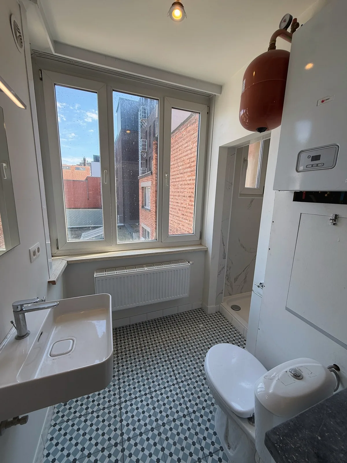 Badkamer met lavabo toilet en raam in studio Antwerpen Zuid